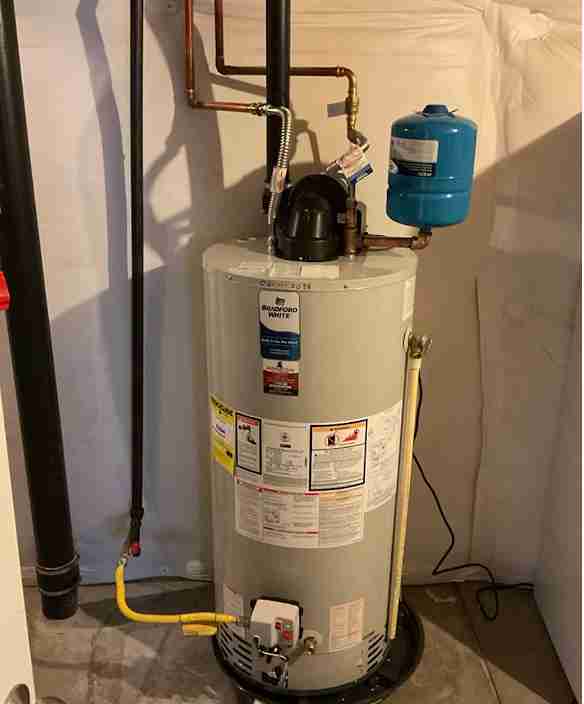 A residential Bradford White water heater with a blue expansion tank and copper piping, professionally installed by New Flow Plumbing