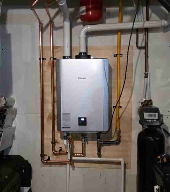A professionally installed Rinnai tankless water heater mounted on a wooden backer board, showing copper and PVC piping, adjacent to a water filtration system, typical of New Flow Plumbing's expert work